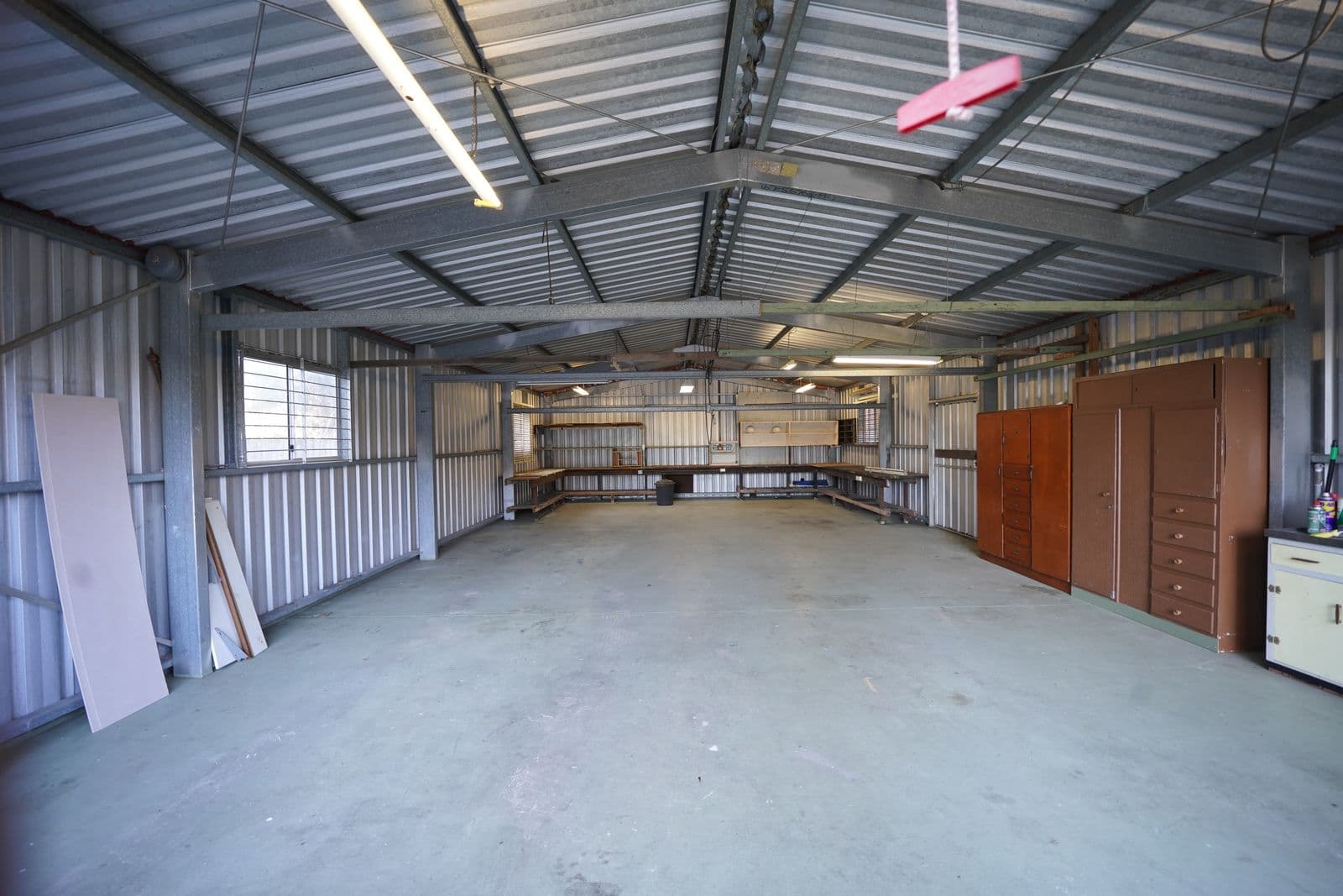 Empty garage workshop with a bare concrete slab floor and workbenches