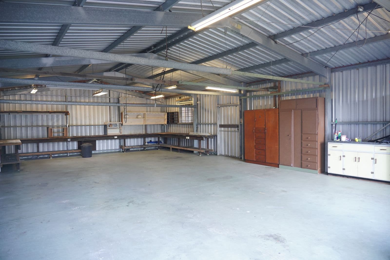 A Miami-style workshop garage interior with cabinets, workbenches and a bare concrete floor